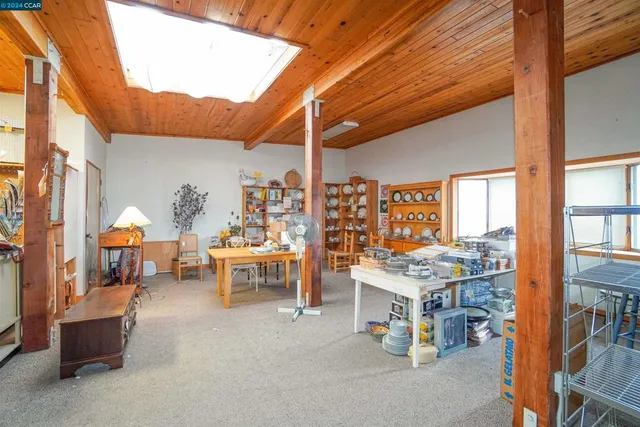 a room with lots of tables a large window and chairs