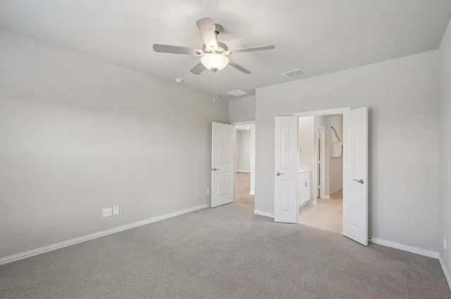 an empty room with chandelier fan and closet area