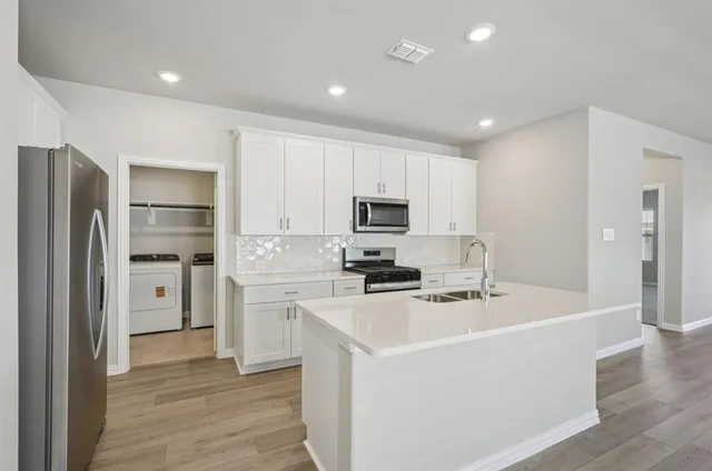 a kitchen with white cabinets and stainless steel appliances