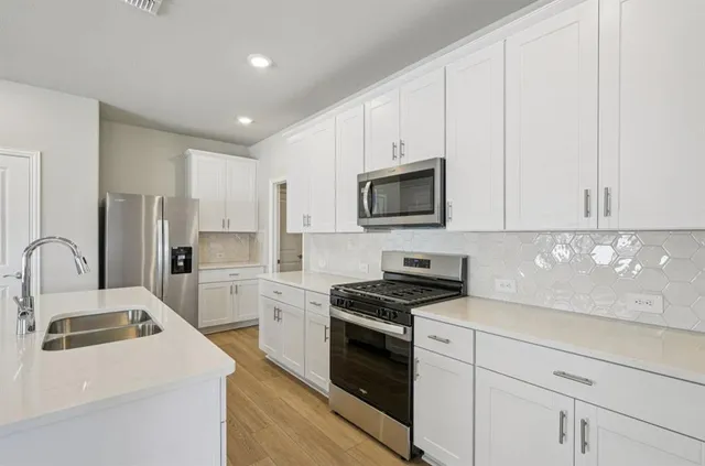 a kitchen with white cabinets stainless steel appliances and sink