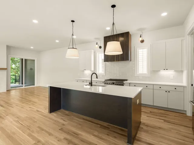 a large kitchen with kitchen island a stove a sink dishwasher a refrigerator and a wooden floor