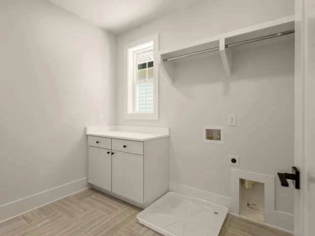 an empty room with wooden floor cabinet and windows