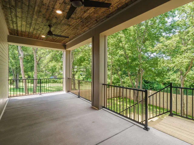 a view of a backyard with large trees and wooden fence
