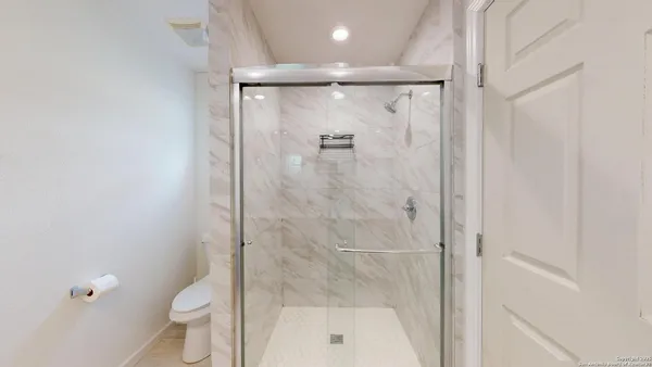 a bathroom with a shower a toilet and a glass door
