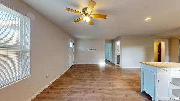 a view of an empty room with window and a kitchen