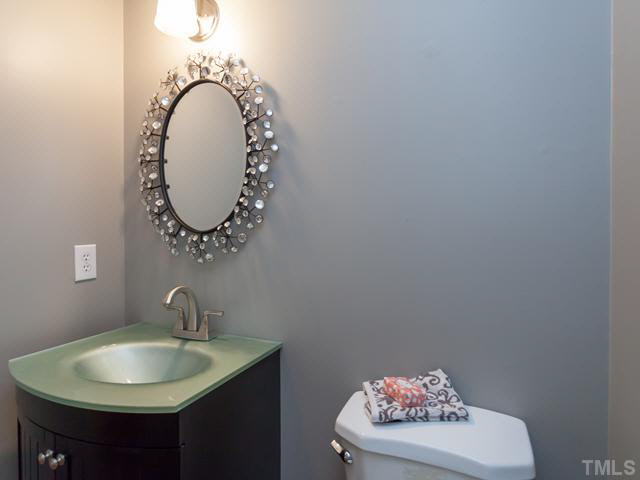 2337 Florida Court Raleigh, NC 27615 - Photo 21 of 25 The power room features hardwood floors and an updated vanity with a glass sink. The mirror over the vanity does not convey.