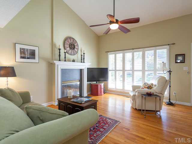 The open family room features planation shutters, hardwood floors, gas fireplace and ceiling fan.