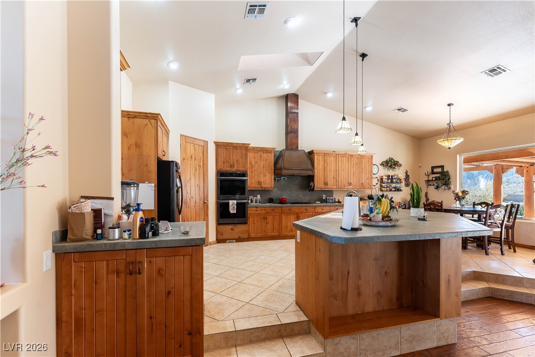 13675 Racel Street Las Vegas, NV 89166 - Photo 11 of 55 Kitchen with decorative light fixtures, light tile patterned floors, brown cabinets, high vaulted ceiling, and tasteful backsplash