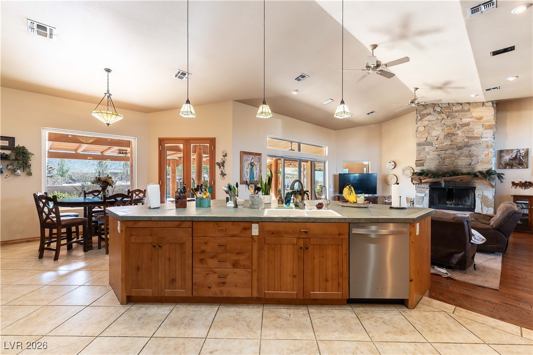 13675 Racel Street Las Vegas, NV 89166 - Photo 13 of 55 Kitchen featuring brown cabinetry, pendant lighting, a stone fireplace, dishwasher, and light tile patterned flooring