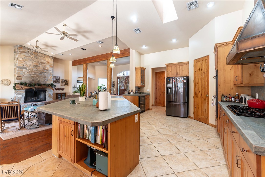 13675 Racel Street Las Vegas, NV 89166 - Photo 14 of 55 Kitchen with open shelves, light tile patterned floors, exhaust hood, a stone fireplace, and stainless steel refrigerator with ice dispenser