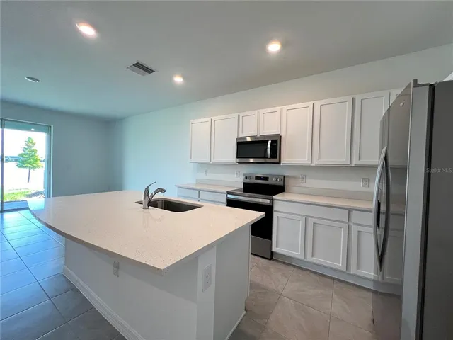 a kitchen with stainless steel appliances a microwave sink refrigerator and cabinets