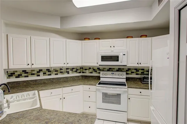 a kitchen with granite countertop white cabinets and white appliances