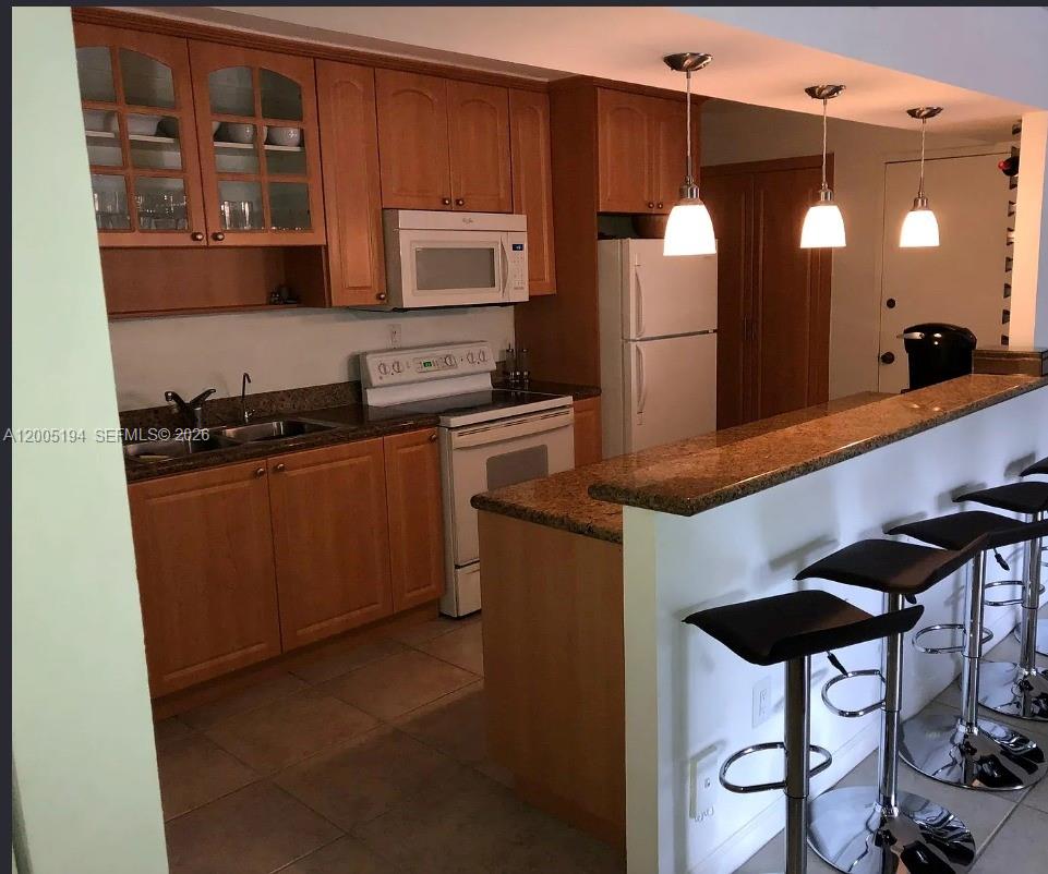 7705 Southwest 86th Street, Unit B211 Miami, FL 33143 - Photo 3 of 22 a kitchen with stainless steel appliances granite countertop a refrigerator a stove and a sink with wooden floor