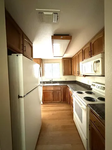 a kitchen with stainless steel appliances a refrigerator a stove a sink and white cabinets