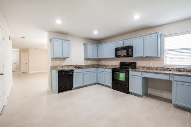 a kitchen with granite countertop white cabinets and stainless steel appliances
