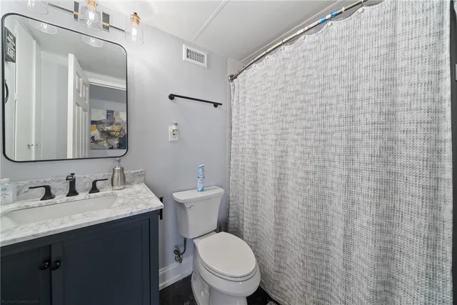 a bathroom with a granite countertop toilet sink and mirror