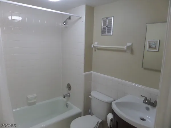 a view of a hallway with wooden floor and a bathroom