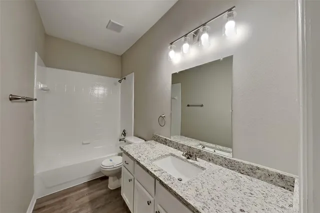 a bathroom with a granite countertop sink a toilet and shower