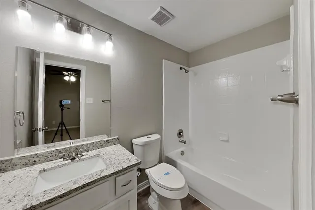 a bathroom with a granite countertop sink toilet mirror and bathtub