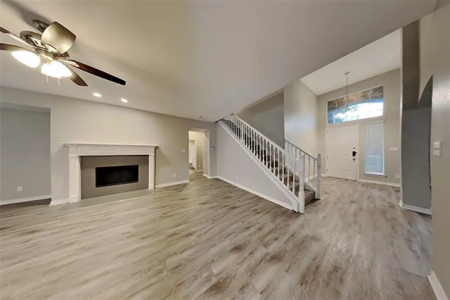 a view of an empty room with wooden floor fireplace and a window