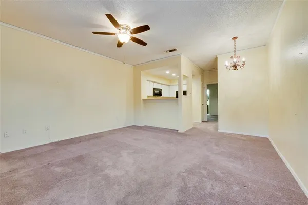 an empty room with a kitchen and a ceiling fan