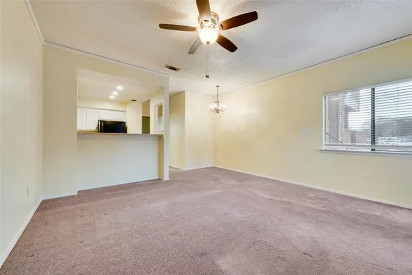 an empty room with chandelier fan and windows