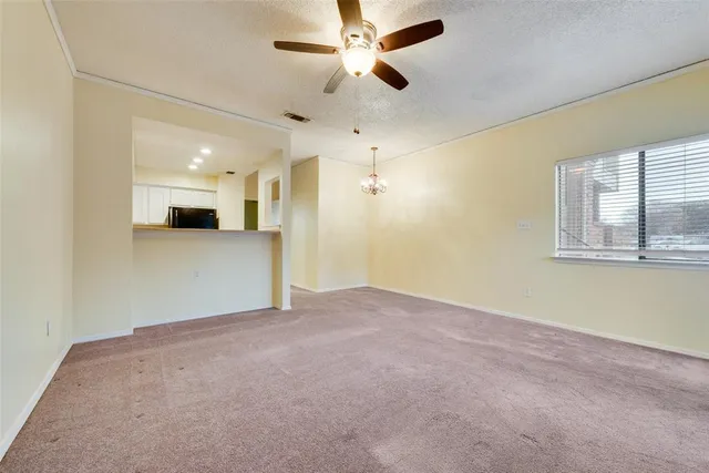 an empty room with chandelier fan and windows