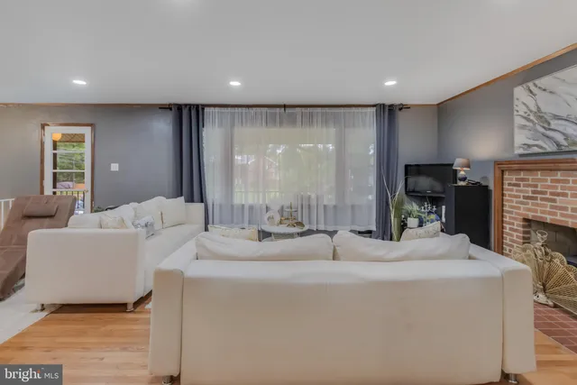 a living room with couches and kitchen view with wooden floor