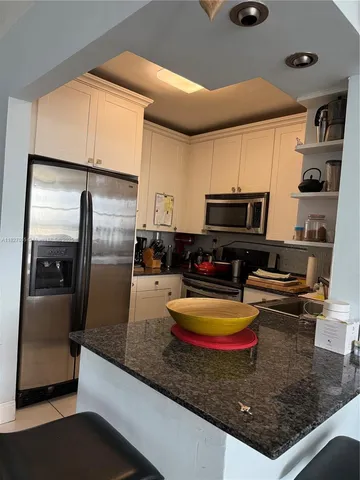 a kitchen with stainless steel appliances granite countertop a sink a microwave and refrigerator