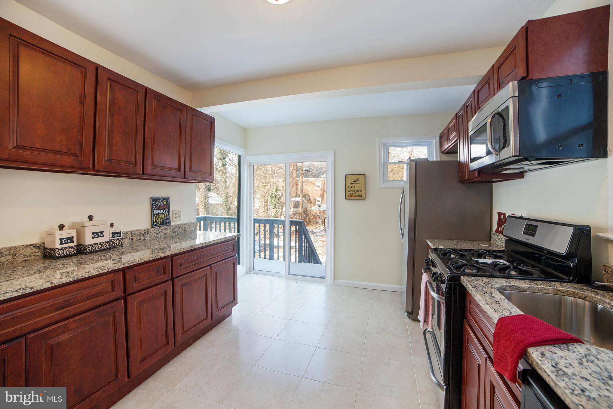 3706 Ferndale Avenue Baltimore, MD 21207 - Photo 10 of 27 a kitchen with stainless steel appliances granite countertop a stove top oven a sink dishwasher and a refrigerator with wooden cabinets