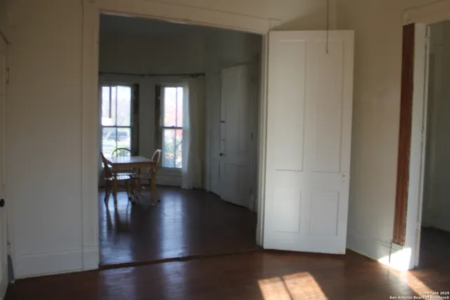a view of empty room with wooden floor and fan