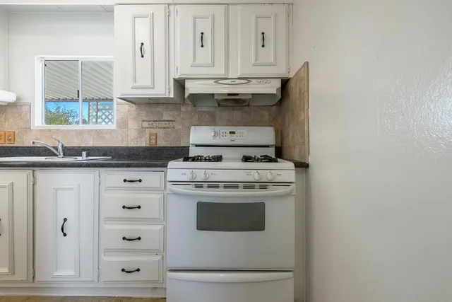 a kitchen with white cabinets and white appliances