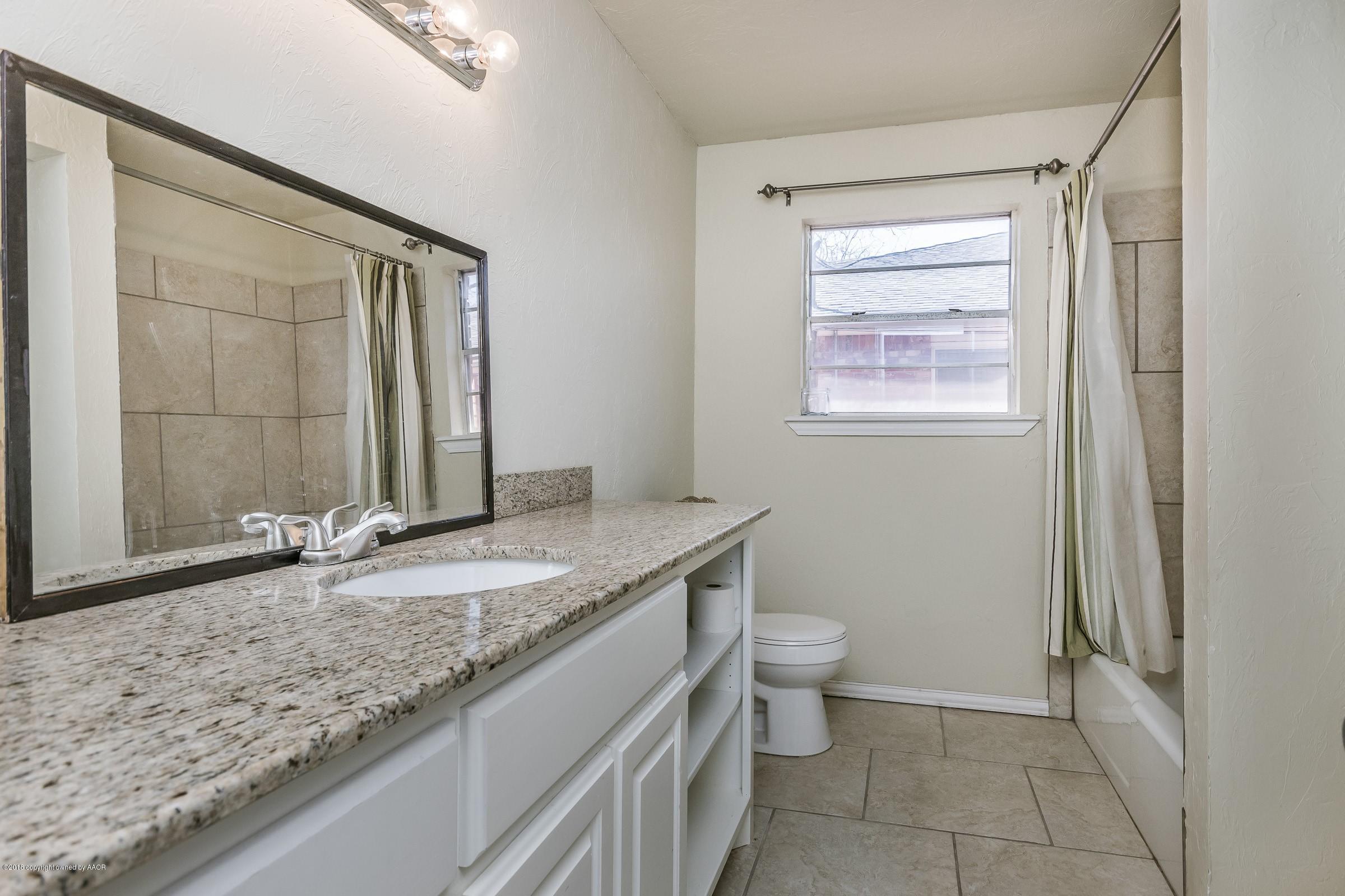 3312 Lombard Road Amarillo, TX 79106 - Photo 18 of 23 a bathroom with a granite countertop sink a toilet and a mirror