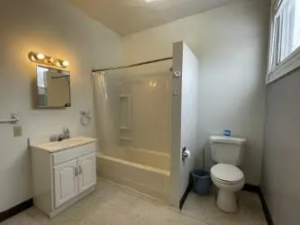 an empty room with wooden floor closet and windows