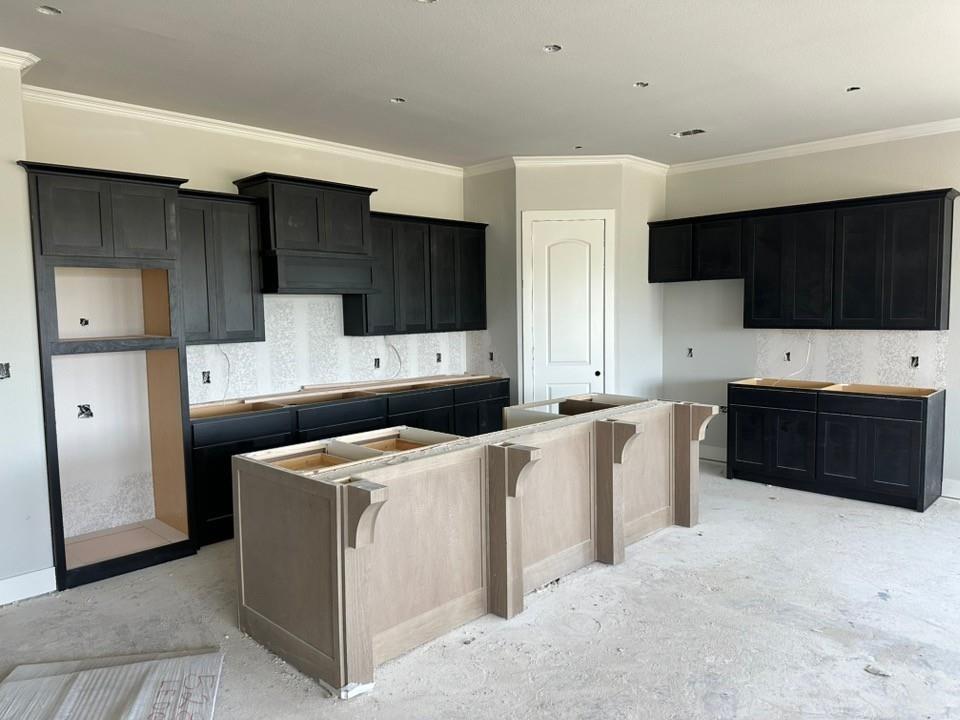 295 Brown Road Leonard, TX 75452 - Photo 8 of 26 Kitchen featuring dark wood-finish cabinetry, a built-in range hood enclosure, crown molding, and recessed lighting