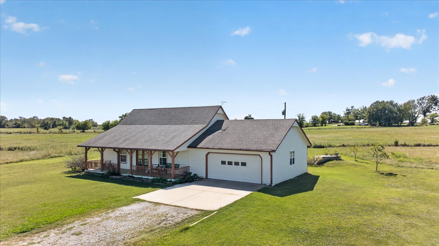 26115 4157th Road Nowata, OK 74048 - Photo 26 of 36 White exterior with dark roof, covered front porch, attached garage, and expansive lawn