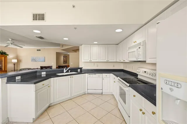 a kitchen with granite countertop white cabinets and white appliances