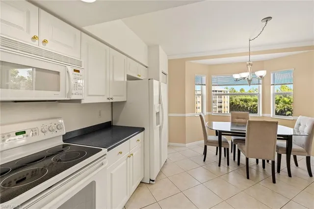 a kitchen with stainless steel appliances granite countertop a stove a refrigerator a white table and chairs