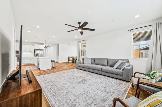 a living room with furniture kitchen view and a chandelier