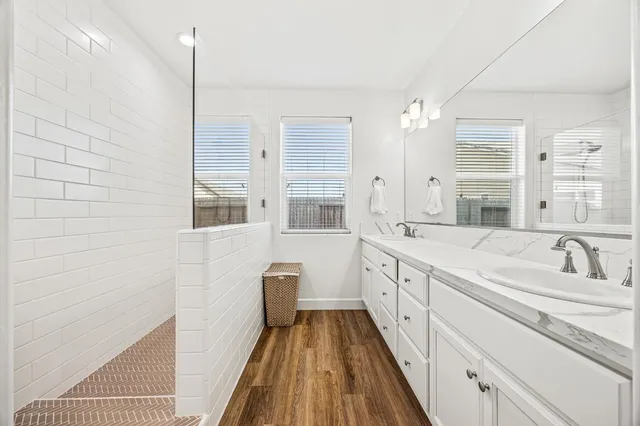 a spacious bathroom with a granite countertop sink a mirror and a shower
