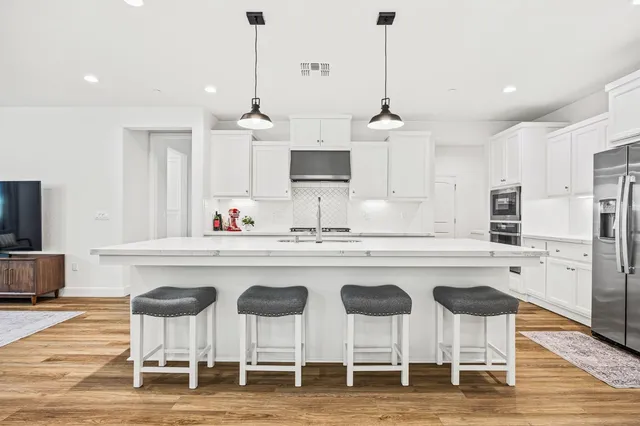 a kitchen with stainless steel appliances kitchen island granite countertop a dining table chairs and sink