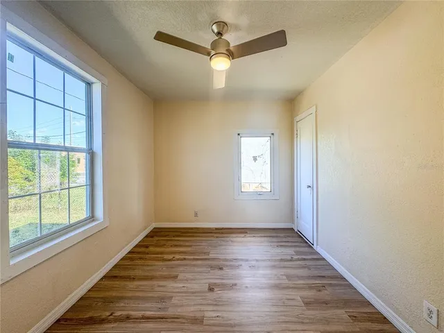a view of an empty room with wooden floor and a window