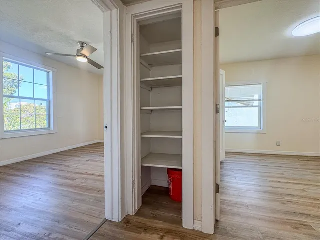 a view of an empty room with wooden floor closet and a window