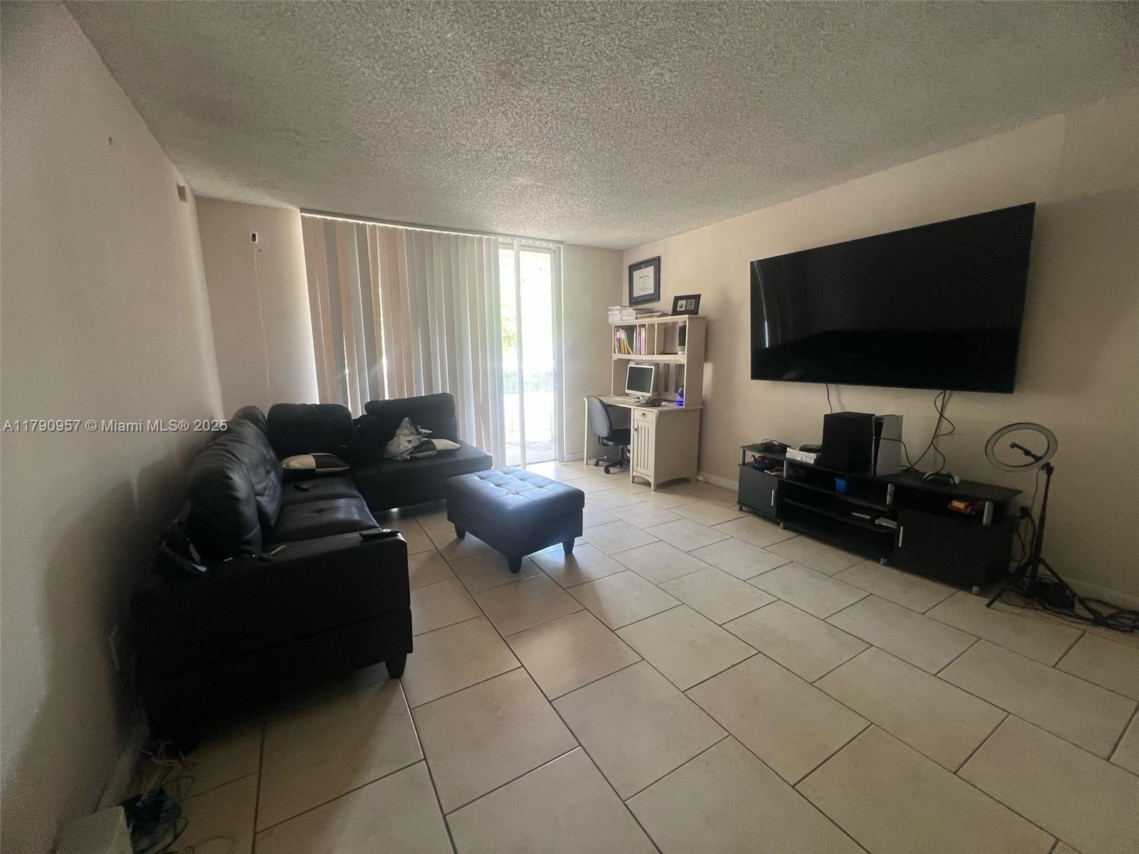 482 Northwest 165th Street, Unit A203 Miami, FL 33169 - Photo 2 of 6 a living room with furniture and a flat screen tv