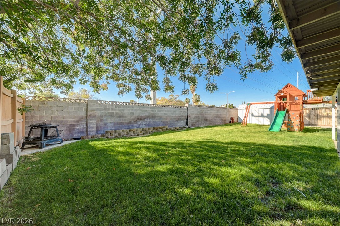 1331 Pinto Road Boulder City, NV 89005 - Photo 42 of 46 A well-maintained lawn with ample space, secured by a sturdy block fence and bordered by lush trees.