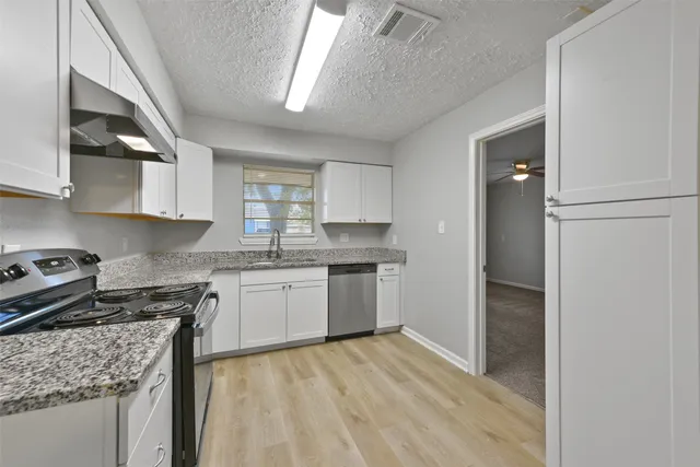 a kitchen with granite countertop a sink stove and refrigerator