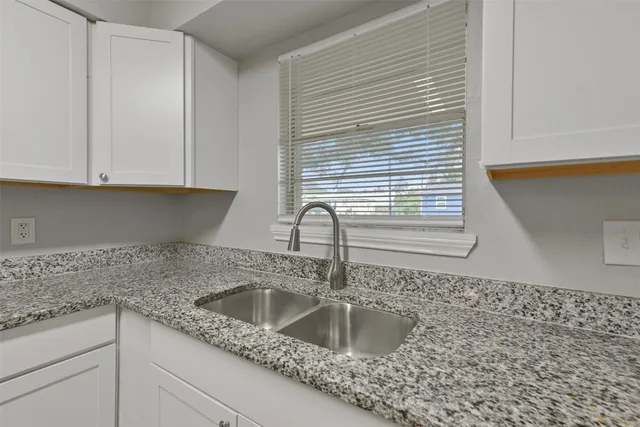 a kitchen with granite countertop a sink and a white cabinets