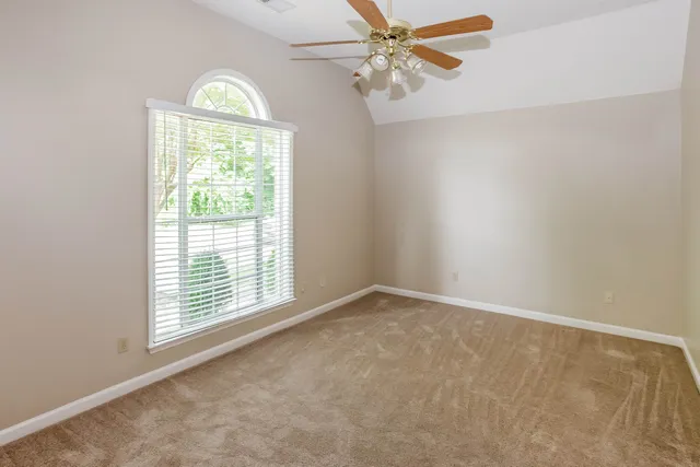 an empty room with windows and ceiling fan