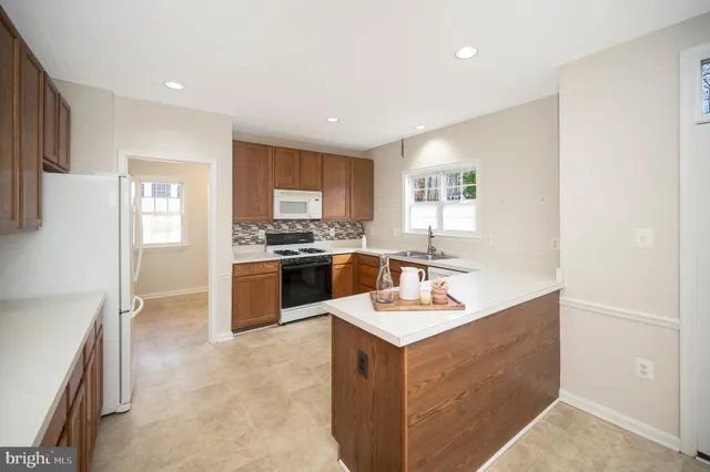 a kitchen with a sink a stove a refrigerator a center island and a window