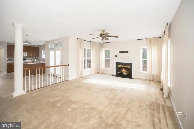 a view of a livingroom with a fireplace a ceiling fan and windows